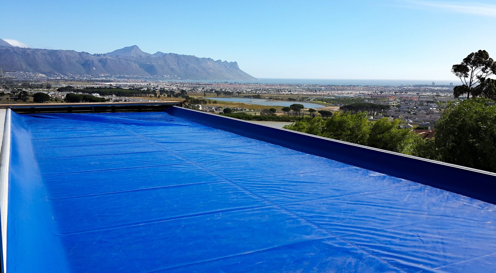 Blue safety cover closed over a pool above Cape Town