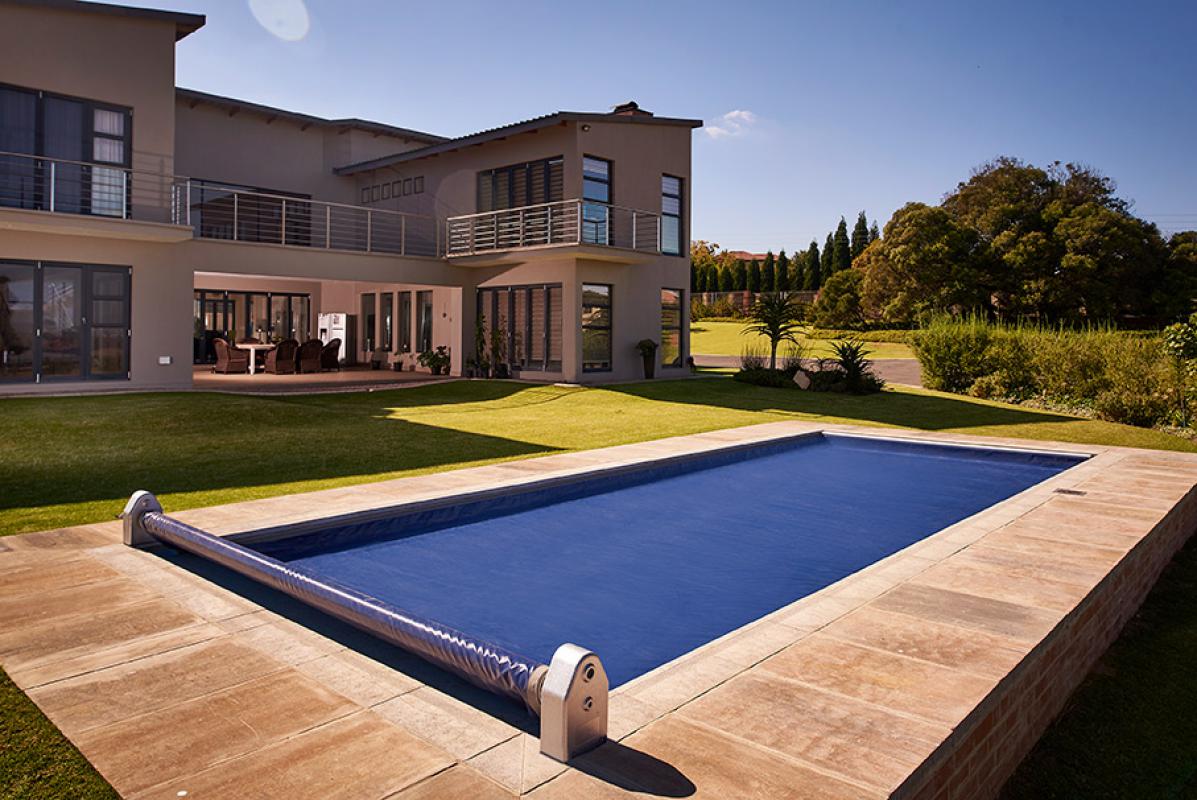 Navy safety cover closed over a pool with the roller in the foreground