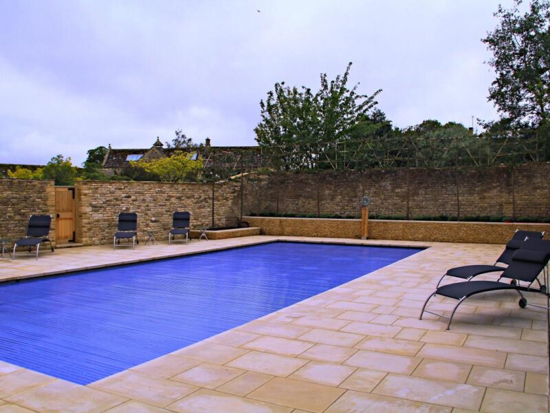 Blue slatted cover closed over a pool in a walled Cotswold garden