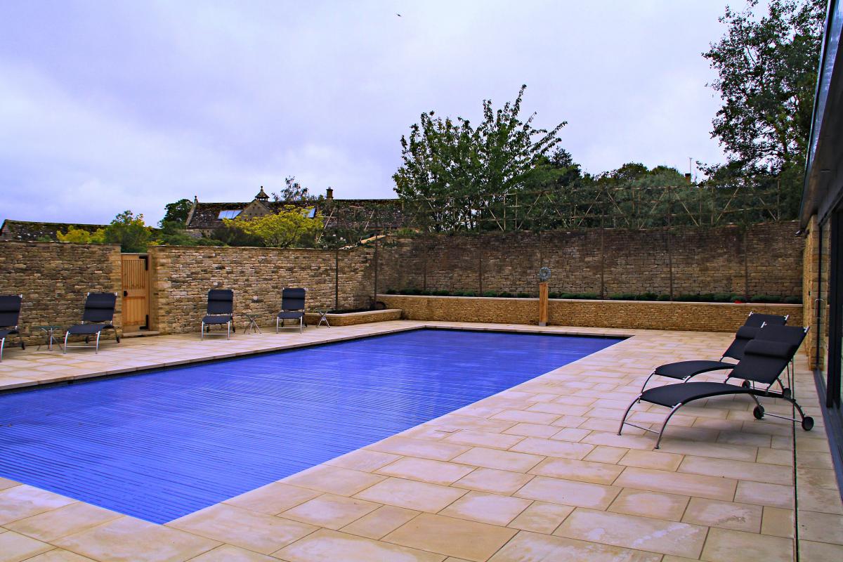 Blue slatted cover closed over a pool in a walled Cotswold garden