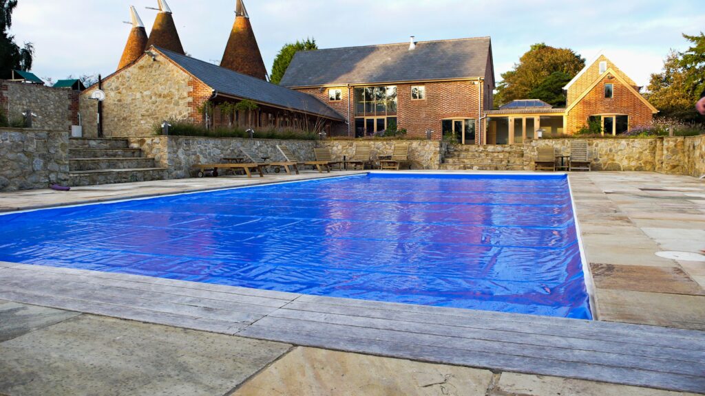 A safety cover closed over a full pool at an English oast house, in flat northern daylight