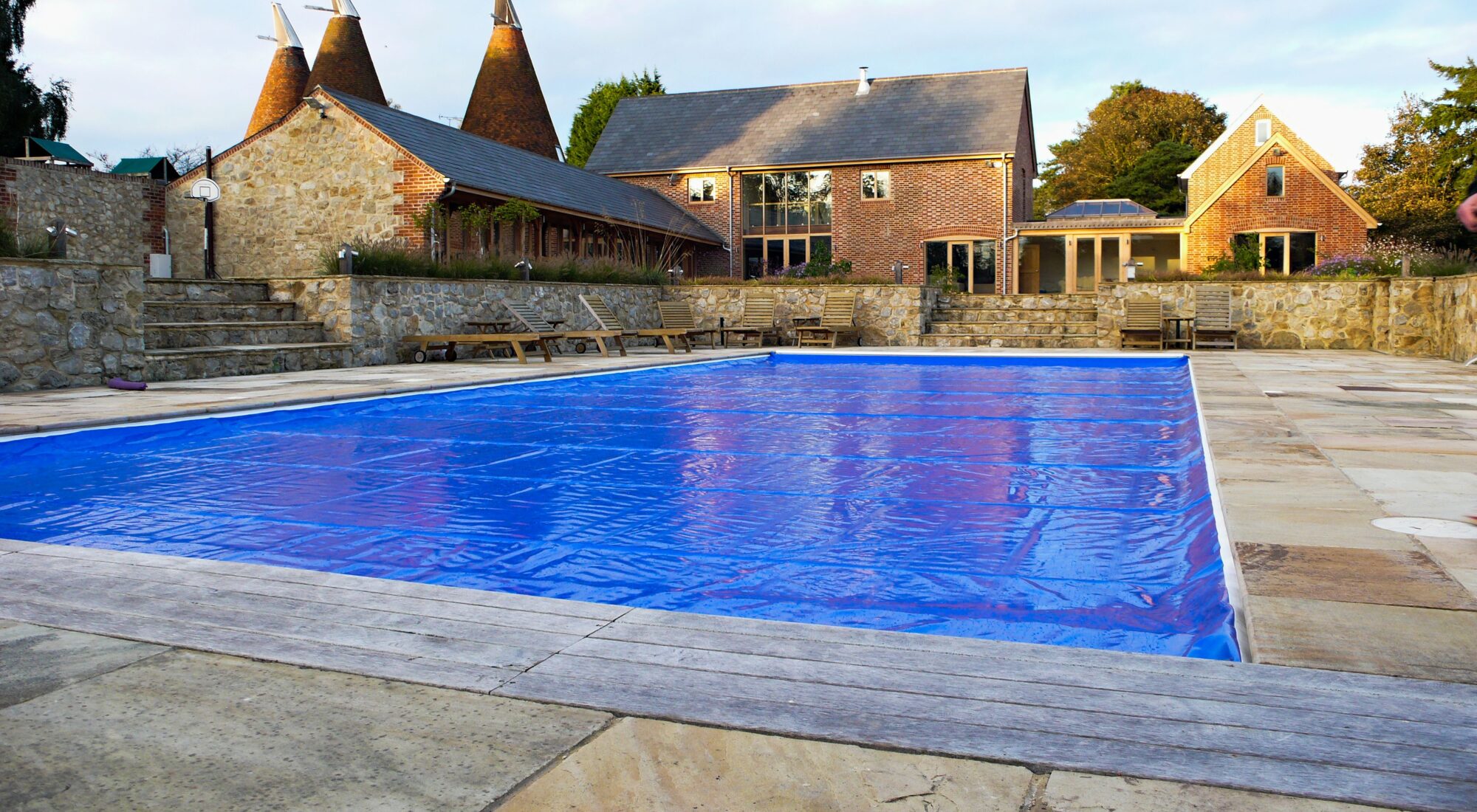 A safety cover closed over a full pool at an English oast house, in flat northern daylight