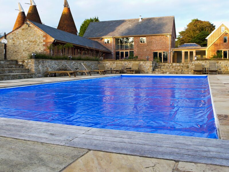 A safety cover closed over a full pool at an English oast house, in flat northern daylight