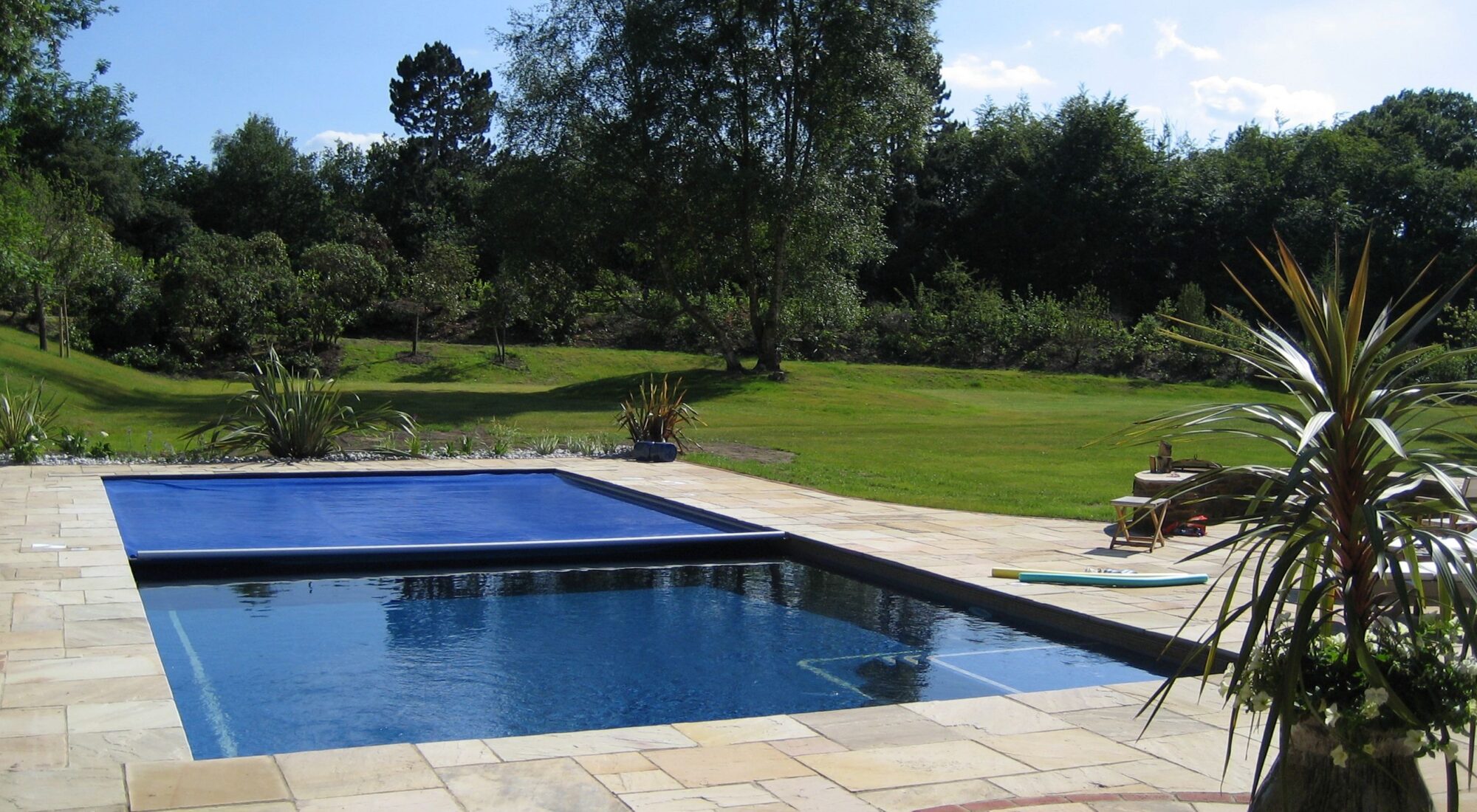 A pool cover half drawn back, with part of the water surface still open.