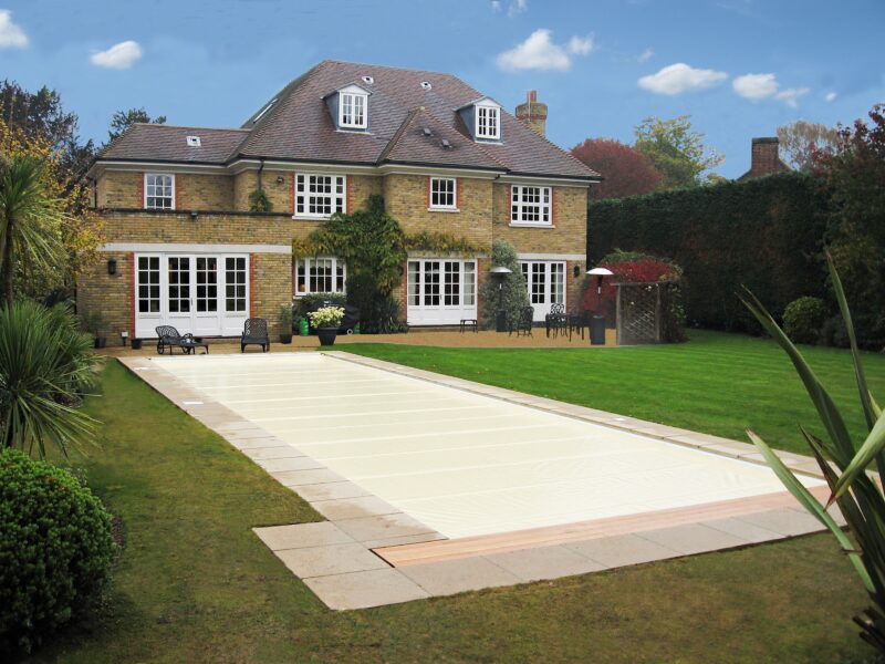 A PoolLock safety cover closed over a domestic pool in an English garden in autumn.
